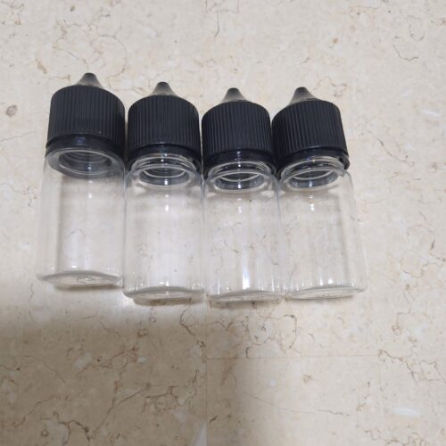 Four empty glass dropper bottles with black caps lined up on a beige marble surface. - Tradedubai.ae Wholesale B2B Market