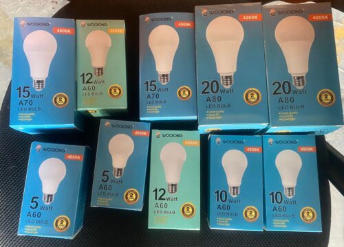 IMG-20260420-WA0001 - Tradedubai.ae Wholesale B2B Market Boxes of Woojong LED bulbs in various wattages (5W, 10W, 12W, 15W, 20W) and color temps (3000K–4000K) arranged on a surface. - Tradedubai.ae Wholesale B2B Market