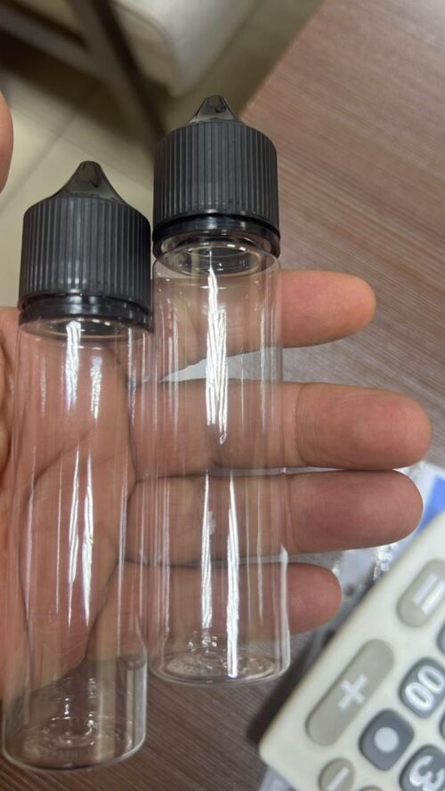 IMG-20260420-WA0003 - Tradedubai.ae Wholesale B2B Market Two empty clear plastic dropper bottles with black caps being held between fingers. - Tradedubai.ae Wholesale B2B Market